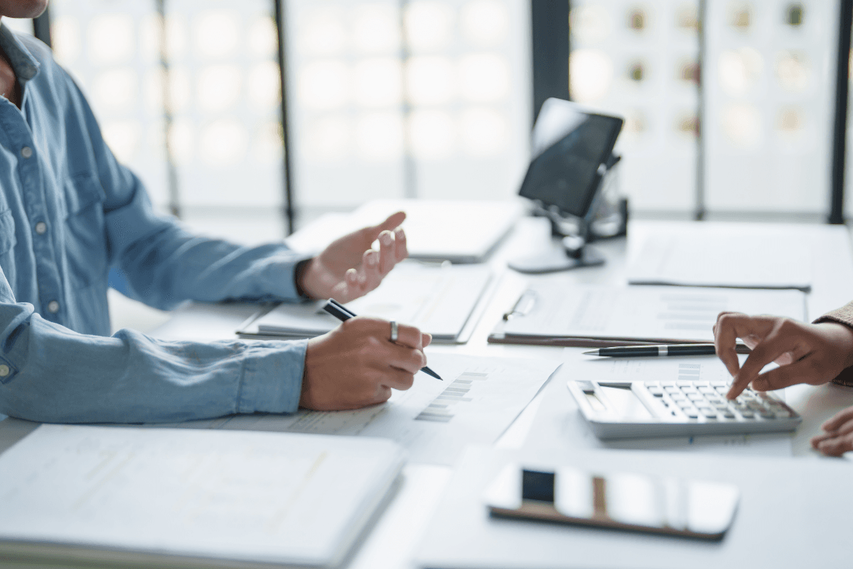 Two people reviewing papers and a calculator at a desk
